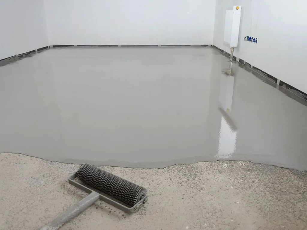 Worker broom-finishing freshly placed concrete on a residential driveway